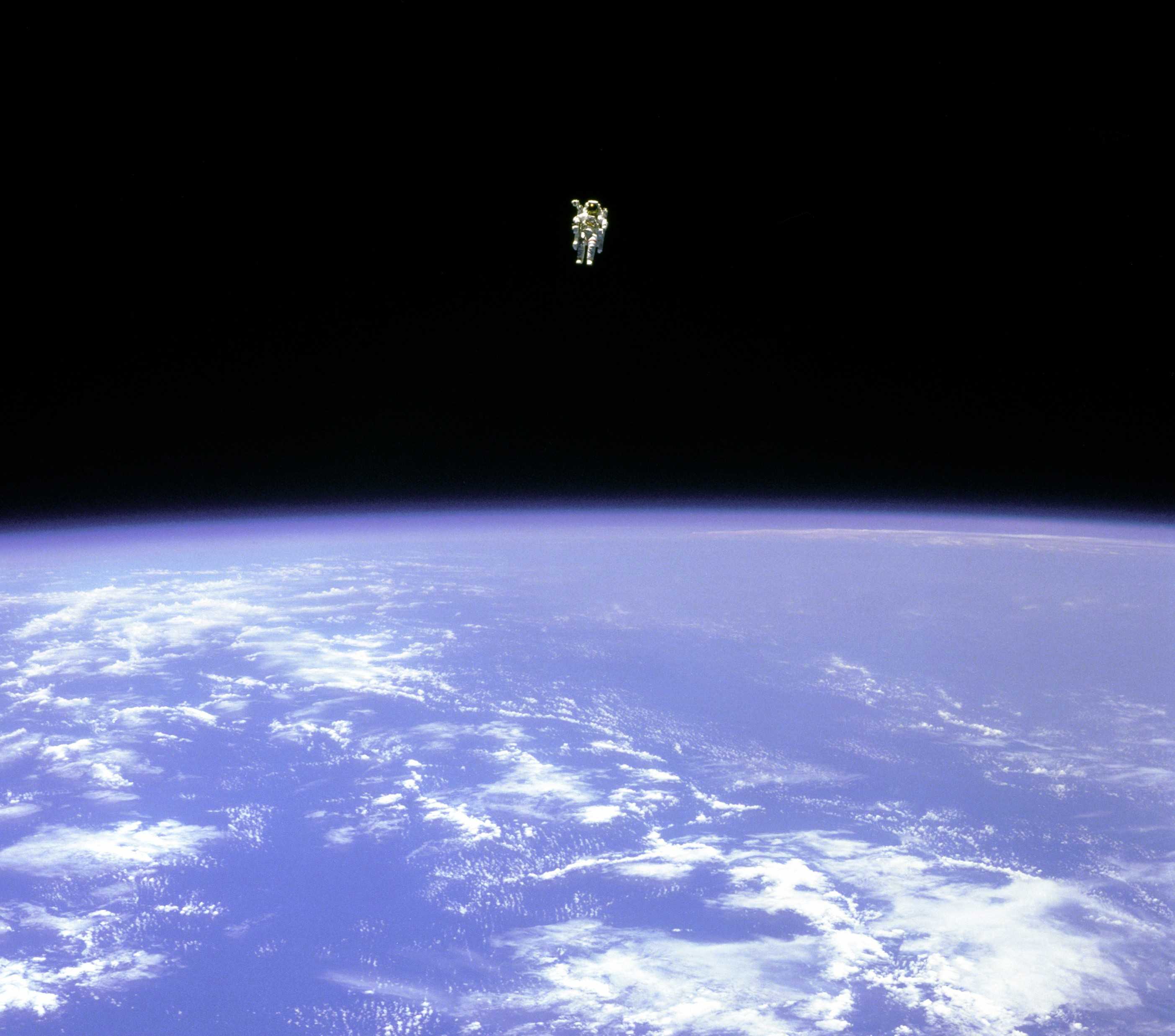 astronaut Bruce McCandless II free floating in a spacesuit over the earth